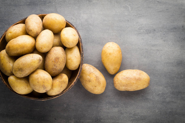 Potato on the bowl, gray background. - Foto, Imagen