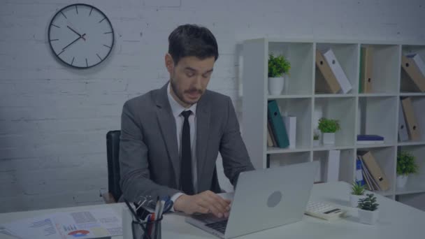 αναστατωμένος επιχειρηματίας πληκτρολογώντας στο φορητό υπολογιστή και μιλώντας στο γραφείο - Πλάνα, βίντεο