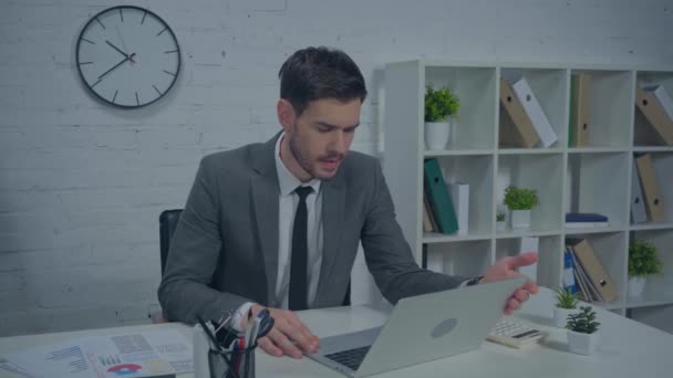 недовольный бизнесмен смотрит на ноутбук и жалуется в офисе - Кадры, видео