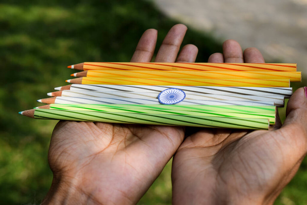 Drapeau indien tricolore tiranga safran, blanc et vert avec chakra Ashoka avec crayons colorés. Des paumes féminines tenant du fil brodé comme concept pour la célébration de la journée de la république indienne représentant le concept de liberté - Photo, image