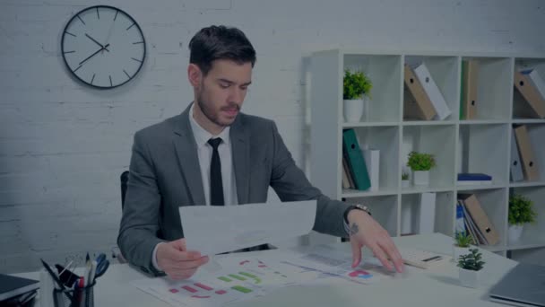 tattooed and displeased businessman looking at documents in office - Footage, Video
