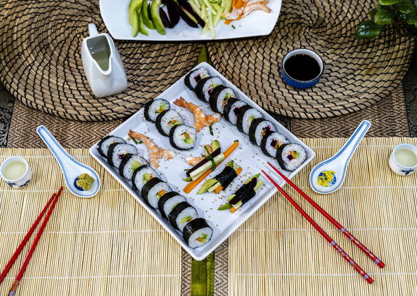 zelfgemaakte sushi traditionele japanse meester het maken van gezonde maki rollen met garnalen komkommer wortel vis - Foto, afbeelding