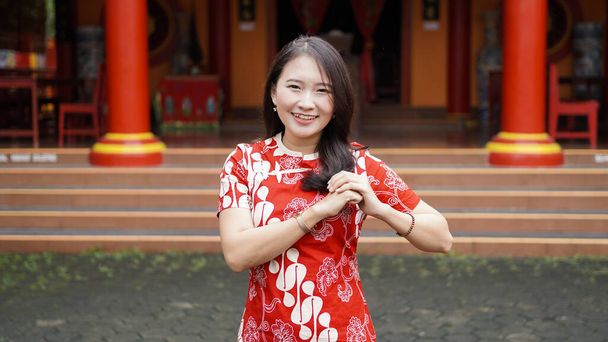 Aziatisch Chinees vrouw in een cheongsam jurk met felicitaties gest bij vihara - Foto, afbeelding