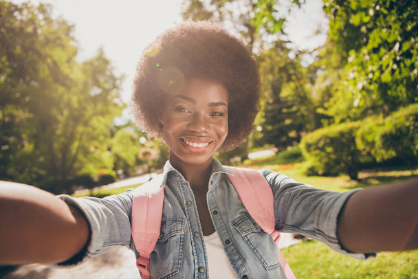 Φωτογραφία πορτρέτο του όμορφου μαύρου δέρματος beautuful κορίτσι λήψη selfie στο πράσινο καλοκαιρινό πάρκο χαμογελώντας φορώντας casual στολή - Φωτογραφία, εικόνα