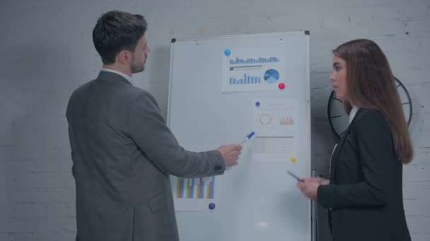 managers pointing at charts while standing near flipchart  - Footage, Video
