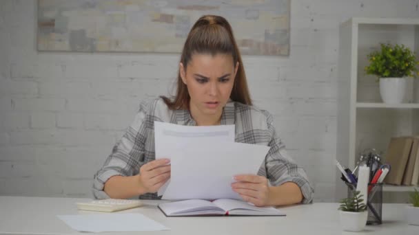 upset woman looking at papers with charts while sitting at workplace  - Footage, Video