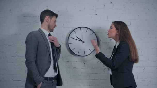 uomo d'affari e uomo d'affari discutendo vicino orologio da parete in ufficio - Filmati, video