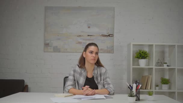 zdenerwowana kobieta siedząca z zaciśniętymi rękami w miejscu pracy  - Materiał filmowy, wideo
