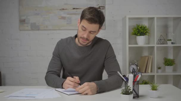 muž psaní v notebooku a při pohledu na grafy na stole - Záběry, video