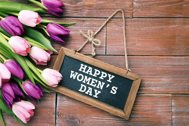 Bouquet of tulips with frame and text Happy Womens Day on brown wooden table - Fotoğraf, Görsel