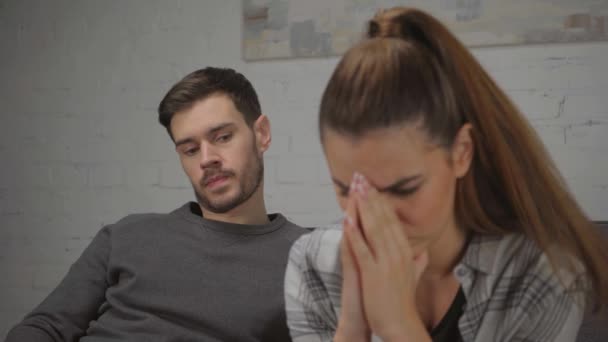 rack focus of man looking at upset girlfriend with praying hands  - Footage, Video
