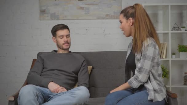 недовольная женщина ссорится с расстроенным парнем, сидя на диване - Кадры, видео