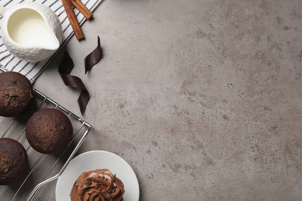 Delicious chocolate muffins and cupcake decorated with cream on grey table, flat lay. Space for text - Photo, Image