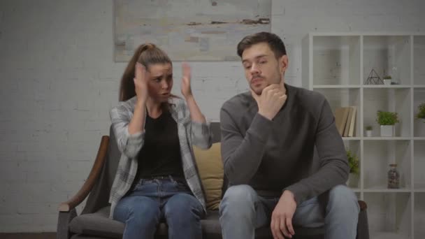 donna scontenta gesticolando e litigando con il fidanzato mentre seduto sul divano - Filmati, video