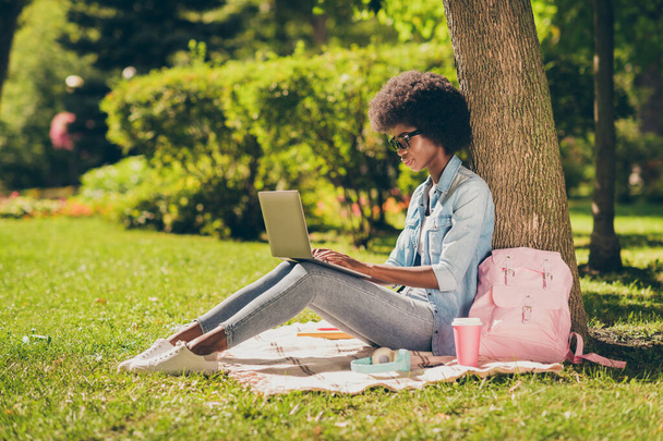 Full length body size side photo of black skinned girl working with laptop education outside in the park wearing glasses near bag - Fotoğraf, Görsel