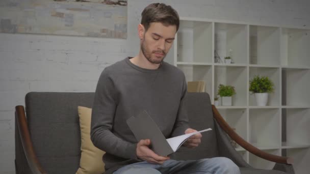 незадоволений чоловік дивиться на теку з документами вдома
 - Кадри, відео