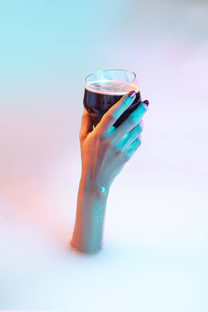 Close up female hand gesturing from the milk bath with soft glowing in neon light - Фото, изображение