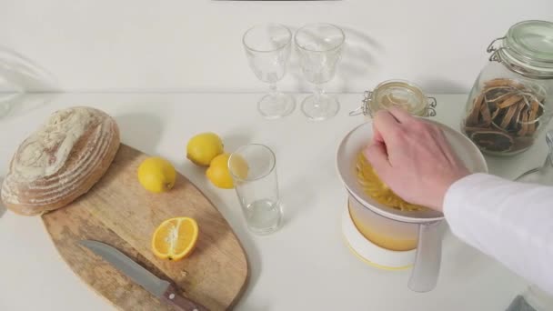 Pov de mão masculina irreconhecível apertando laranjas suculentas com máquina especial, fazendo suco de laranja fresco, derramando-o em vidro - Filmagem, Vídeo