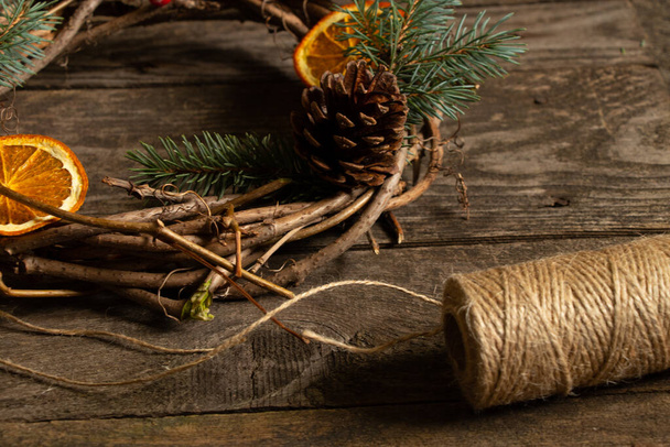 Świąteczny wieniec z winorośli i kulka nici na drewnianym stole, przygotowanie świąteczne - Zdjęcie, obraz