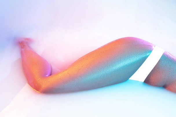 Close up female body in the milk bath with soft glowing in neon light - Φωτογραφία, εικόνα