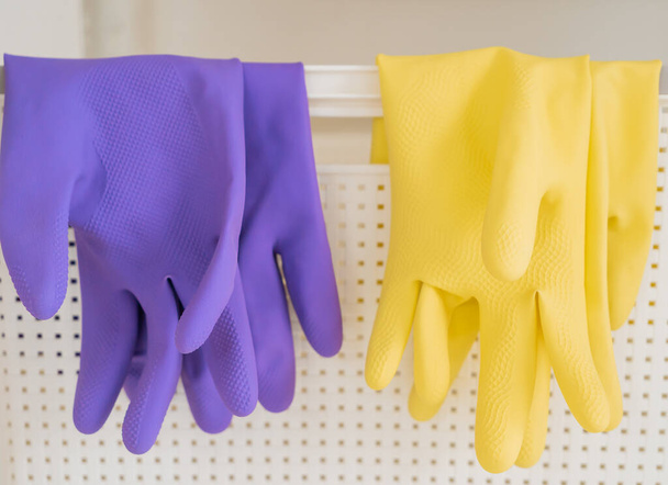 Two pair of rubber gloves is hanging on a white basket for housekeeping cleaning equipments. - Photo, Image