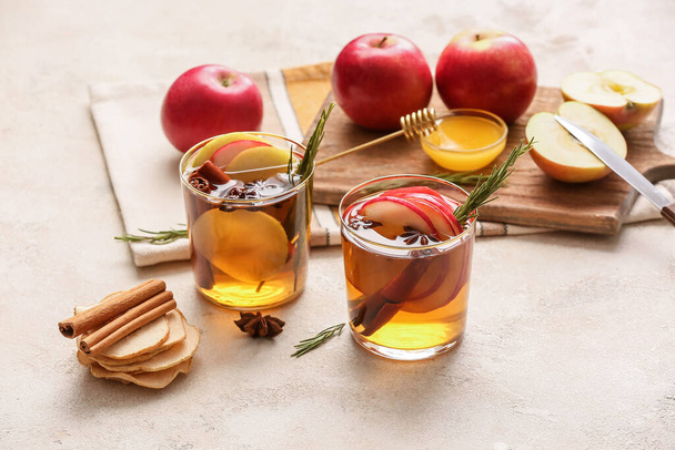 Maukas juoma mausteilla ja omenaviipaleilla laseissa kevyellä taustalla - Valokuva, kuva