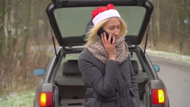 γυναίκα στον Άγιο Βασίλη καπέλο κλήσεις στο smartphone, σπασμένο αυτοκίνητο. - Πλάνα, βίντεο