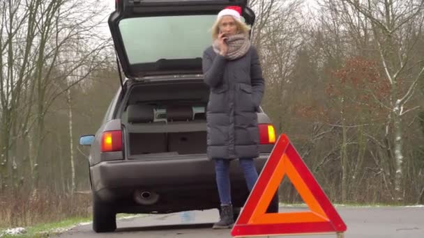 woman in Santa Claus hat calls on smartphone, broken car. - Footage, Video