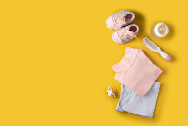 Bebé mamelucos, zapatos, biberón, chupete y peine sobre fondo amarillo - Foto, imagen