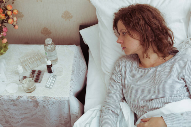 Mulher jovem tem uma gripe e alta temperatura, deitado na cama. - Foto, Imagem