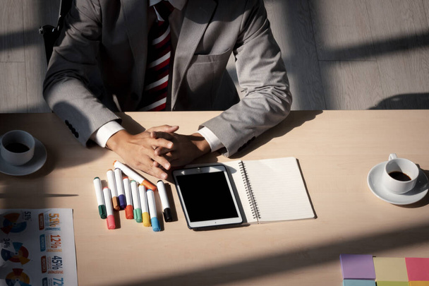 close-up zakenman in formele kleding zitten aan tafel met smart phone, document papier en koffie - Foto, afbeelding