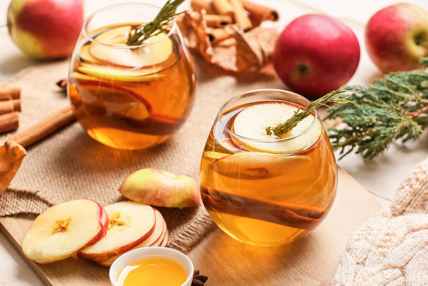 Leckeres Getränk mit Gewürzen und Apfelscheiben in Gläsern auf hellem Hintergrund - Foto, Bild