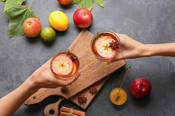 Mulheres segurando bebidas saborosas com especiarias e fatias de maçã em óculos no fundo escuro - Foto, Imagem