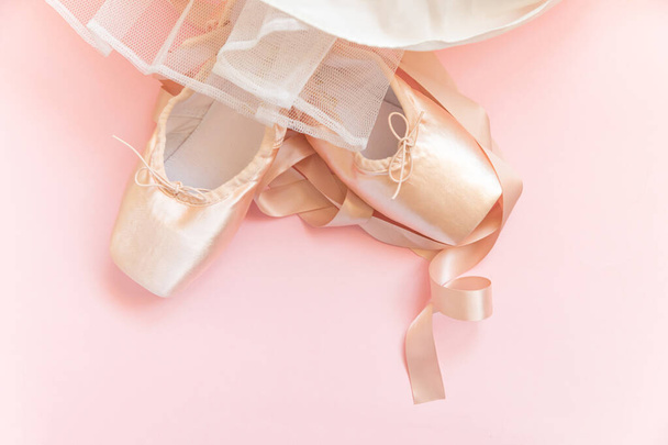 Nuove scarpe da balletto beige pastello con nastro di raso e gonna tutut isolata su sfondo rosa. Ballerina scarpe da punta classiche per allenamento di danza. Concetto di scuola di danza. Vista dall'alto lastra piatta spazio copia - Foto, immagini