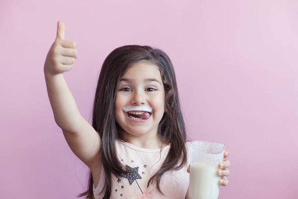 little smiling girl drinking milk from a glass - Φωτογραφία, εικόνα