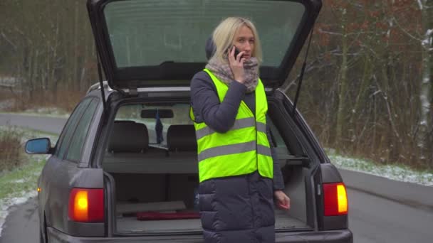 Una donna chiama sul suo smartphone mentre è in piedi in macchina rotta. - Filmati, video