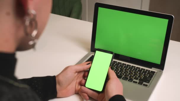 Vista traseira. Fechar o homem homossexual com uma manicure usar tela verde laptop segurando cromo telefone em casa escritório. Homem assistindo conteúdo na tela verde do telefone chromakey. - Filmagem, Vídeo