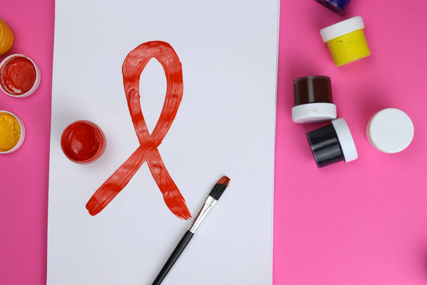 borstel tekent rood lint. internationaal symbool van de strijd tegen aids - Foto, afbeelding