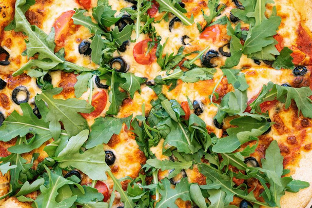 Vegetarian Pizza from the oven. Oven-baked vege pizza with arugula cheese and olives close up view - Zdjęcie, obraz