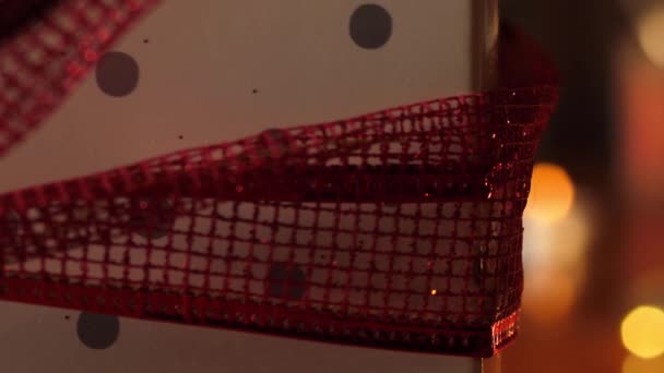 Červený dárek zabalený stužkou na teplých bokeh světlech  - Záběry, video