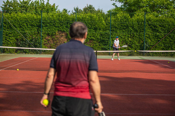 Senioren spelen tennis op een tennisbaan buiten, gezonde levensstijl concept - Foto, afbeelding