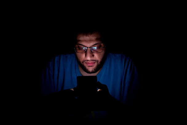 Portrét chlápka z Blízkého východu, jak kontroluje telefon v tmavé místnosti - Fotografie, Obrázek