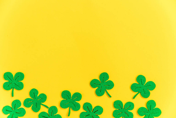 St Patricks Day background. Simply minimal design with green shamrock. Clover leaves isolated on yellow background. Symbol of Ireland. Lucky fortune wish concept. Flat lay top view layout copy space - Photo, Image