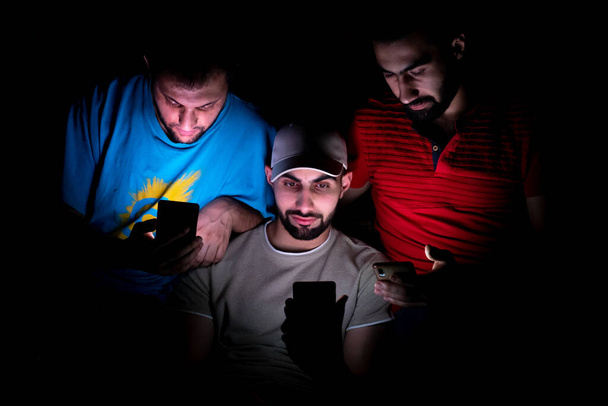 portrait of middle eastern guys setting together in a dark room - Photo, Image