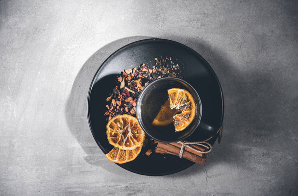 Fruit tea with cinnamon and dried orange in a cup - teacup on gray table. Top view, overhead - Fotoğraf, Görsel