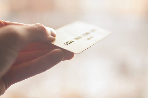 tarjeta bancaria de color oro en las manos sobre un fondo de luz solar - Foto, imagen