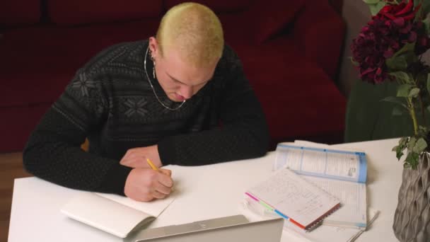Studente omosessuale caucasico uomo utilizzando laptop scrivere informazioni sui compiti a casa in notebook, lavoro online da casa, studio lontano online. - Filmati, video