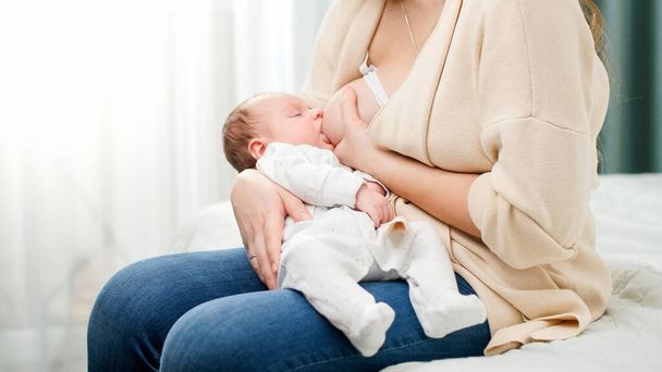 Netter kleiner Junge, der auf den Händen der Mutter liegt und Muttermilch saugt. Konzept der gesunden und natürlichen Babynahrung. - Foto, Bild