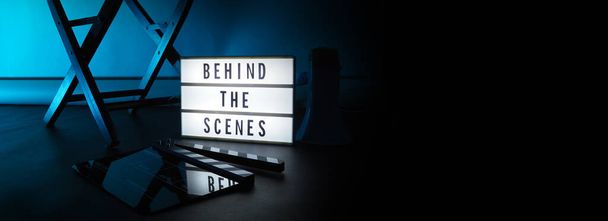 Behind the scenes letterboard text on Lightbox or Cinema Light box. Movie clapperboard megaphone and director chair beside. Background LED color change loop. static camera in video production studio. - Photo, Image