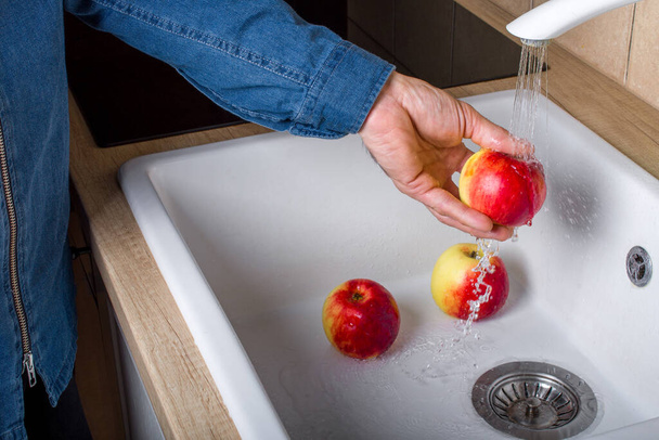Чоловік миє яблука під краном, крупним планом
. - Фото, зображення